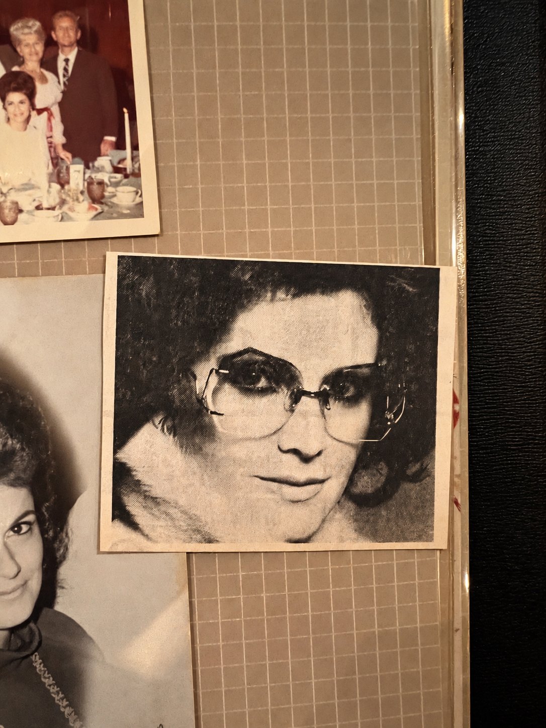 A scrapbook page with a black and white portrait of a woman in glasses beside older family photographs