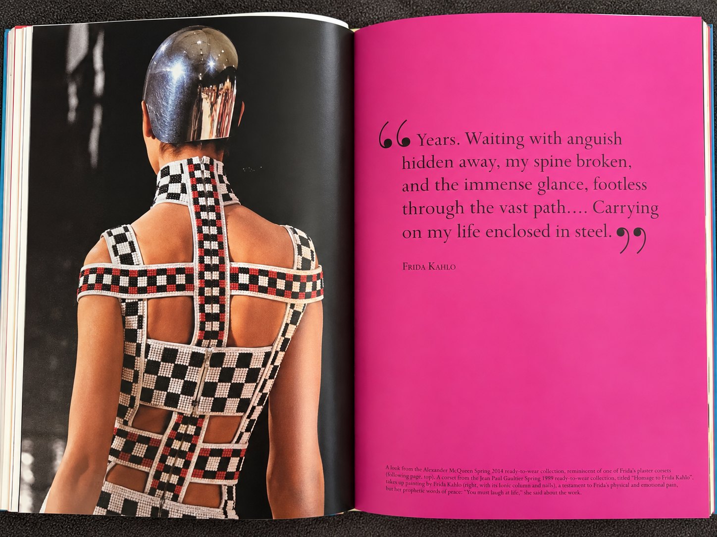 An open book spread: a checkerboard beaded harness dress photographed from behind on the left, a hot pink page carrying a Frida Kahlo quotation on the right