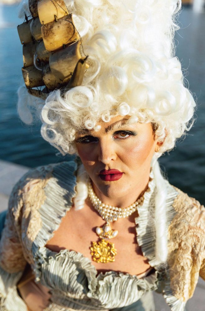 Close portrait in a white wig with a ship headpiece