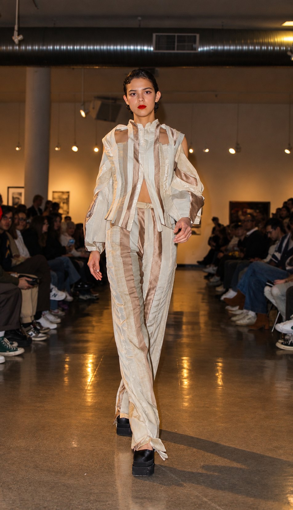 A model walking toward camera in a cream and taupe striped jacket and trousers