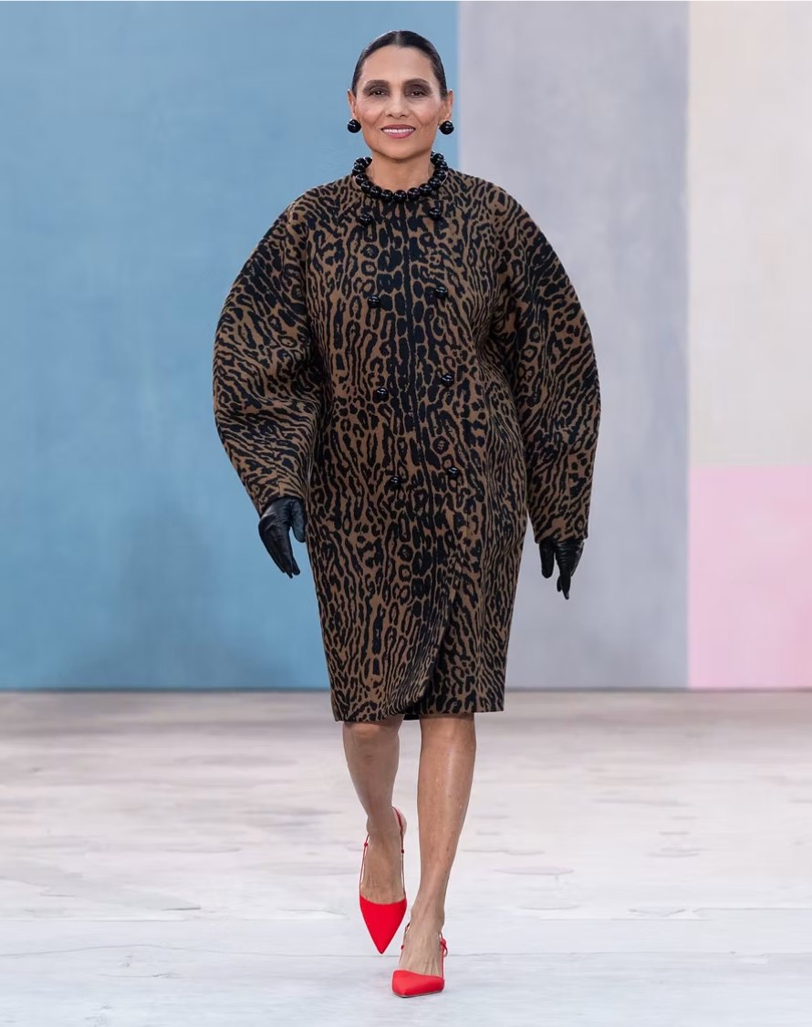 The photographer Ming Smith walking a runway in a leopard print cocoon coat, black gloves and red slingbacks