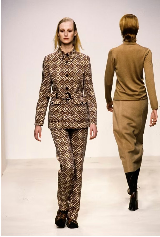 Two Prada looks: a brown diamond-print belted jacket and trousers, and a camel knit with a long skirt seen from behind